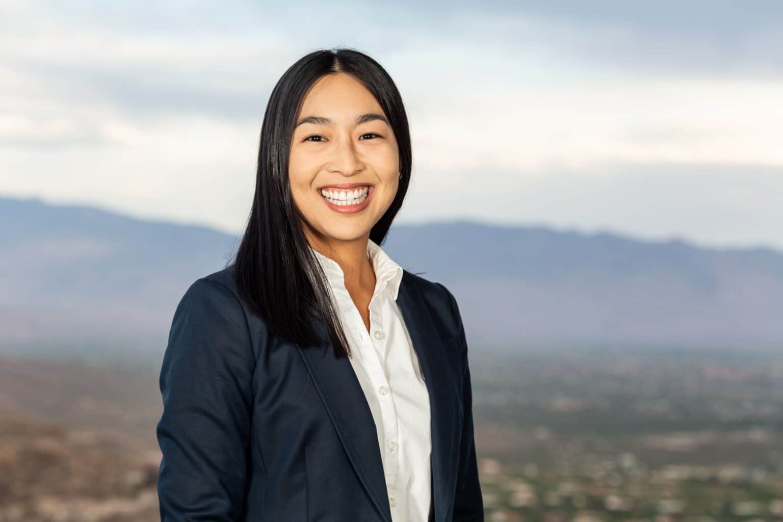 a smiling woman standing in front of a mountain