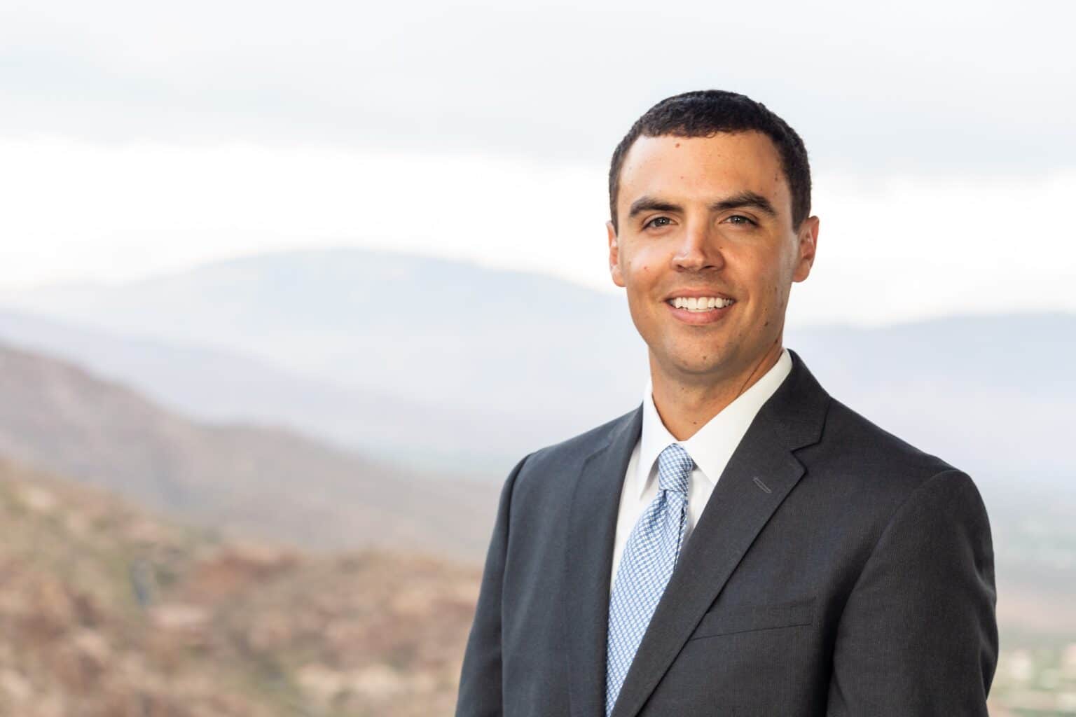a man wearing a suit and tie smiling at the camera